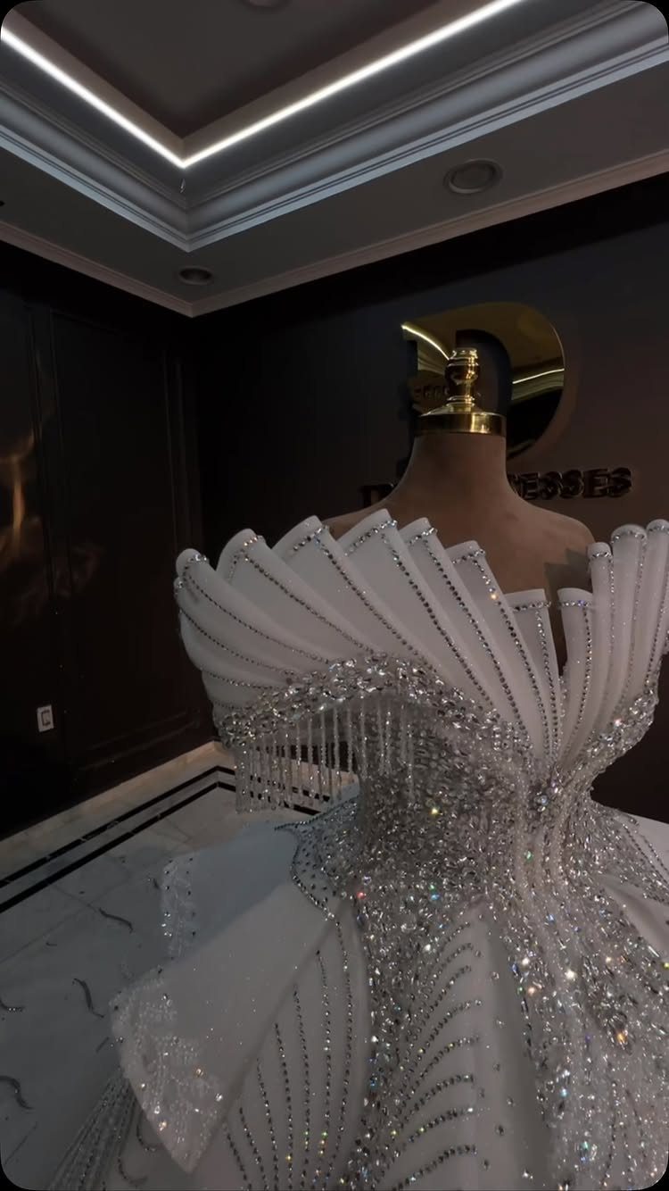 2026 Wedding Dresses: 12 Bridal Styles to Know Right Now 10 A white wedding gown with silver sequins and sculptural pleated fabric on a mannequin.