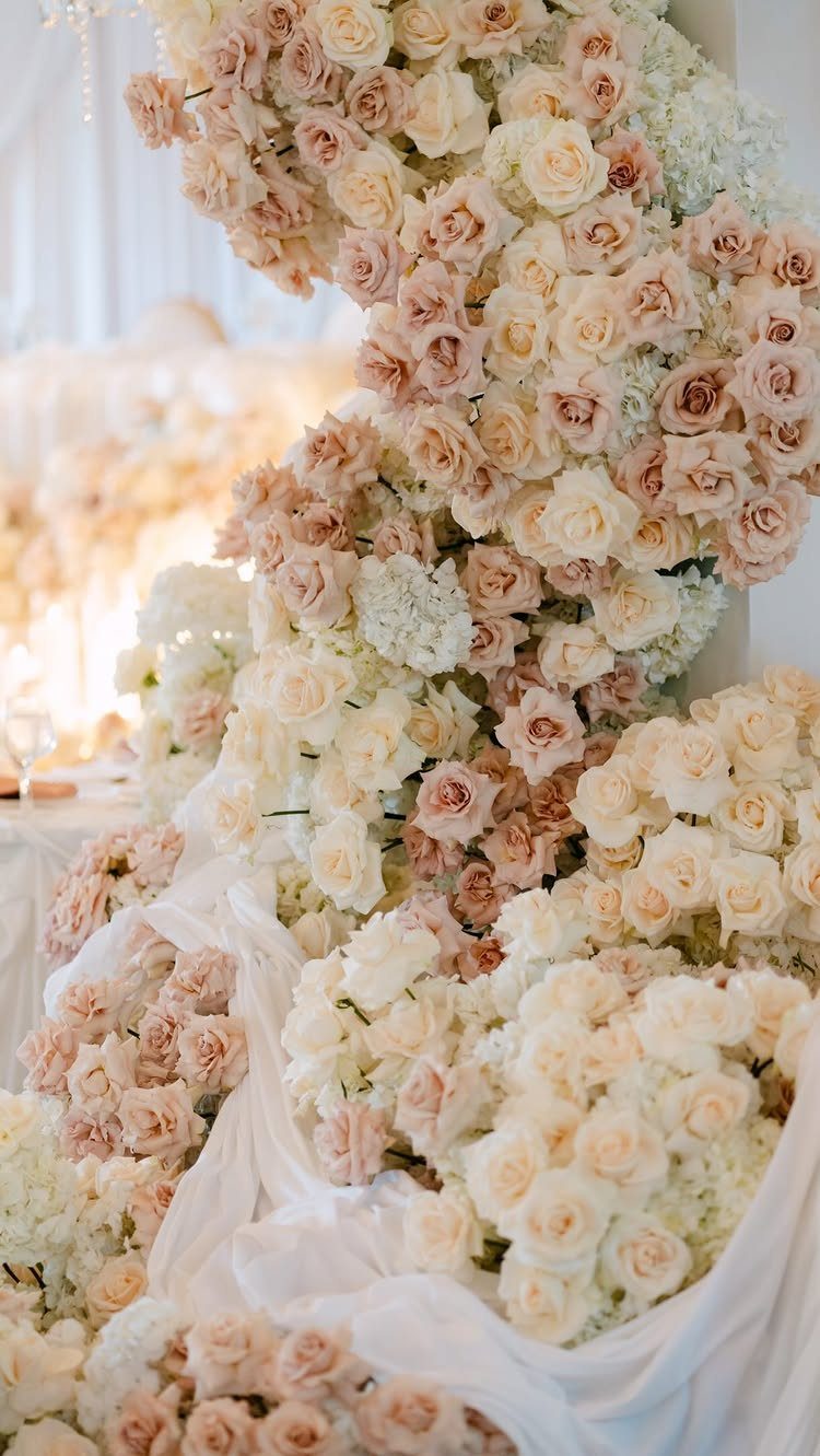 Blush Wedding Colors: 9 Palettes That Work at Actual Weddings 5 Cascading floral arrangement of blush pink and ivory roses and hydrangeas draped over white fabric.