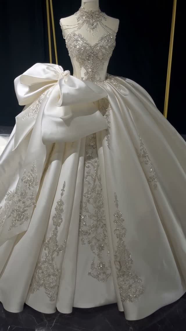An ivory wedding dress with a large waist bow and silver beadwork on a mannequin.