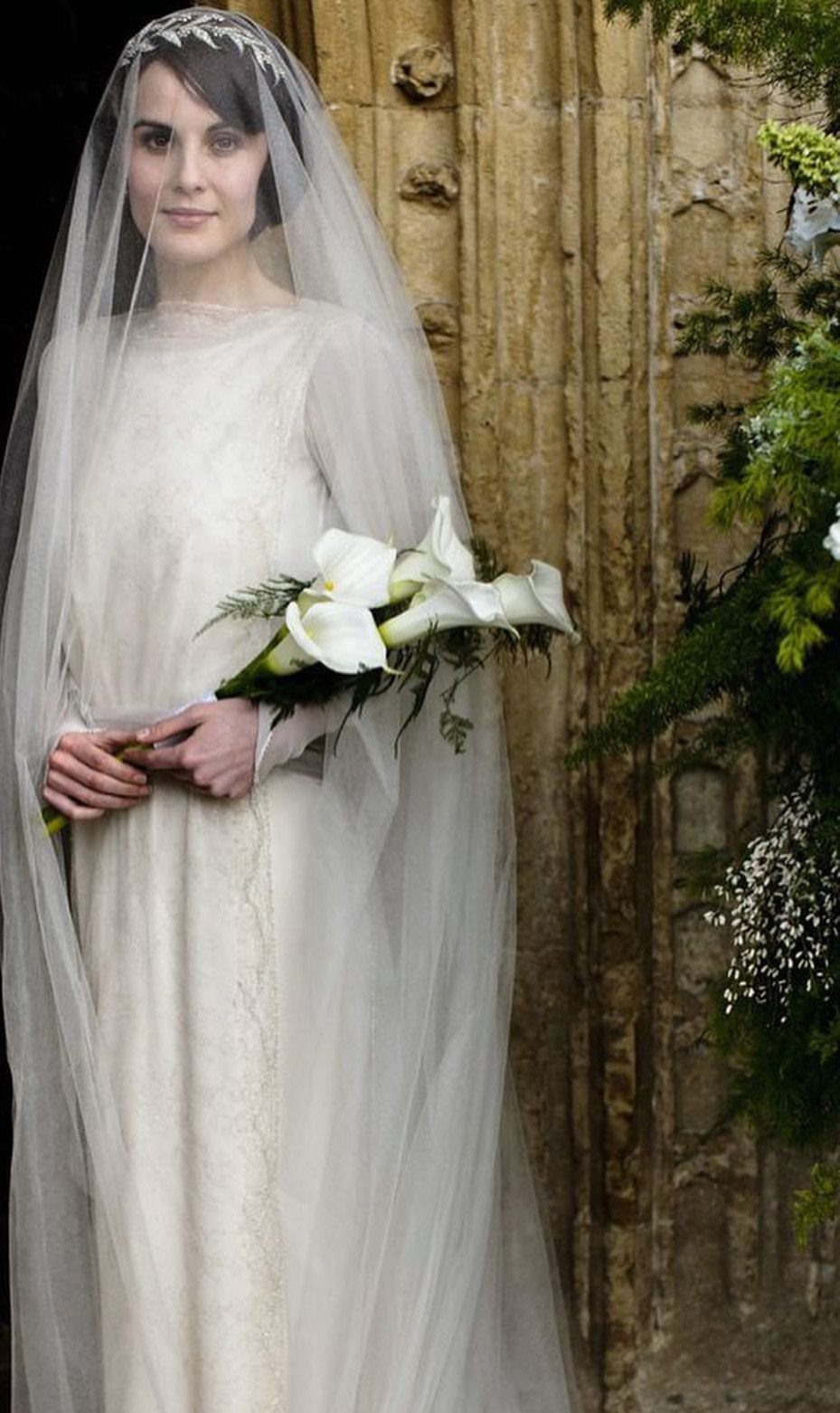 6 Classy Vintage Wedding Dress Finds That Hold Up 3 A woman in a long-sleeved cream vintage wedding dress holding white calla lilies.
