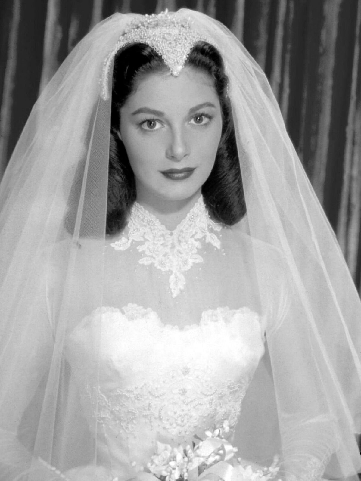 6 Classy Vintage Wedding Dress Finds That Hold Up 4 A woman in a vintage lace wedding dress and long veil posing for a portrait.