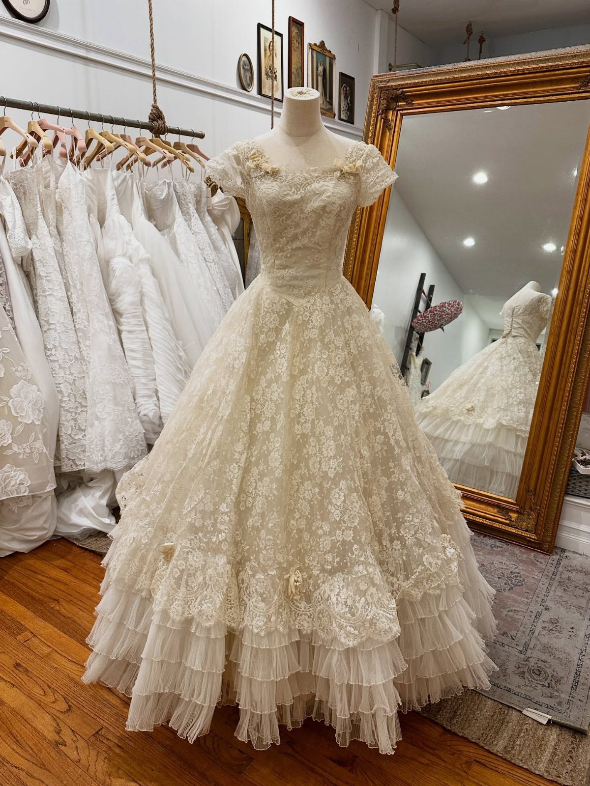 6 Classy Vintage Wedding Dress Finds That Hold Up 2 An ivory vintage wedding dress with floral lace and a tiered tulle skirt on a mannequin.