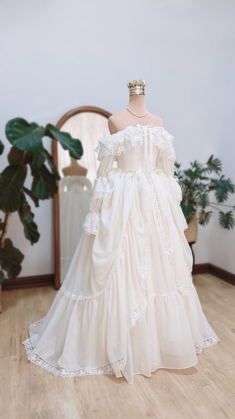 6 Classy Vintage Wedding Dress Finds That Hold Up 6 An ivory lace and ruffled vintage wedding dress displayed on a mannequin indoors.