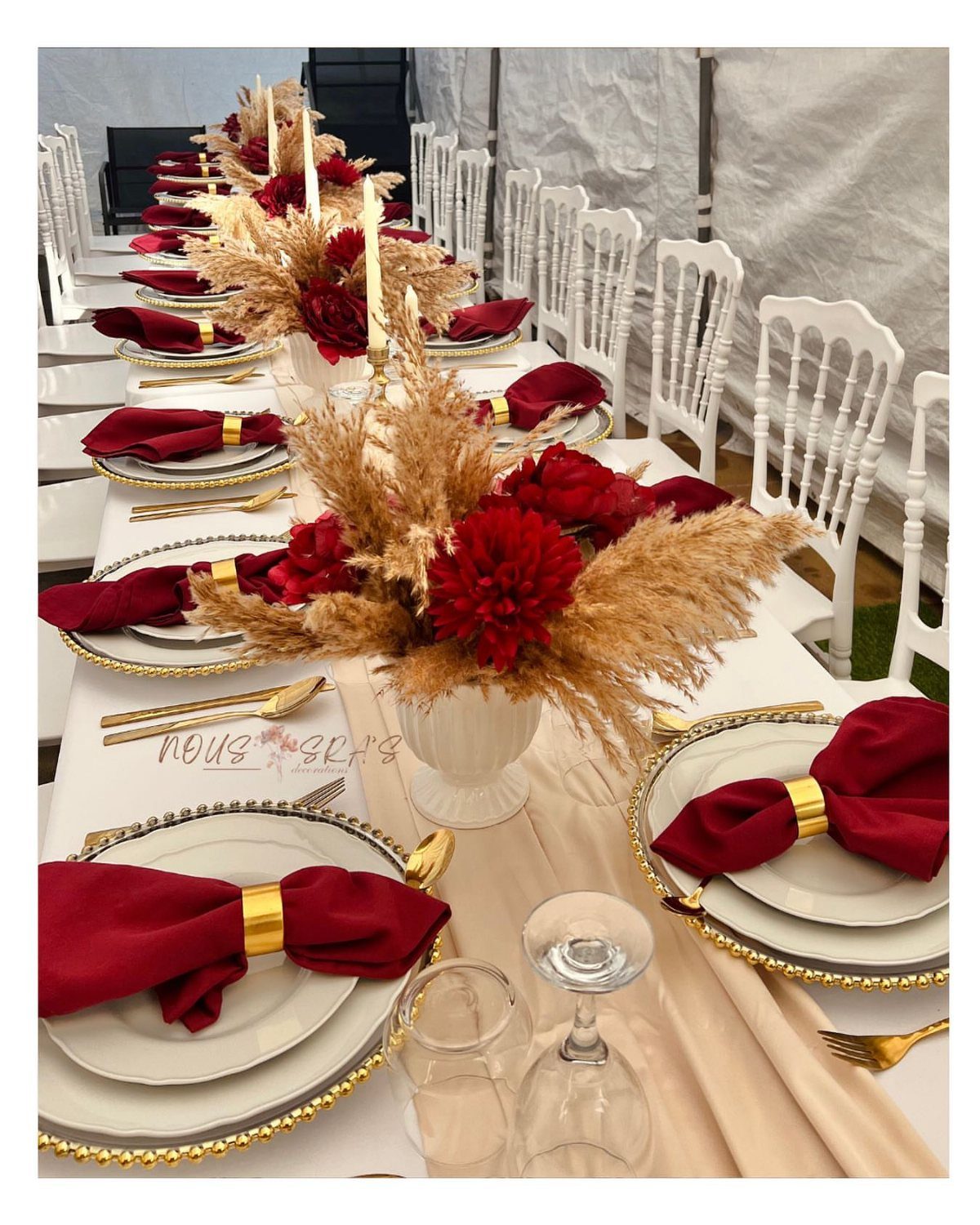 Dark Red Wedding Colors: 20 Ideas for Mood and Palette 13 A long wedding table decorated with red flowers, cream runners, and gold-rimmed plates.
