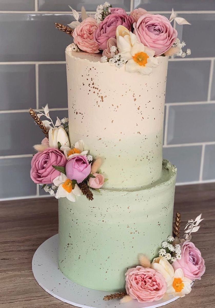 Two-tier ombre wedding cake with sage green and cream frosting decorated with dusty rose flowers.