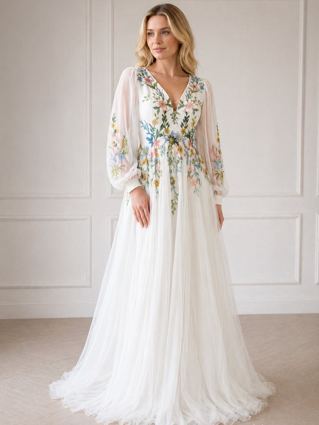 A blonde woman wearing a white wedding dress with colorful floral embroidery and sheer sleeves.