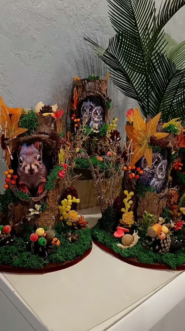Woodland centerpieces with moss, mushrooms, and small squirrel and owl figures inside tree trunks.