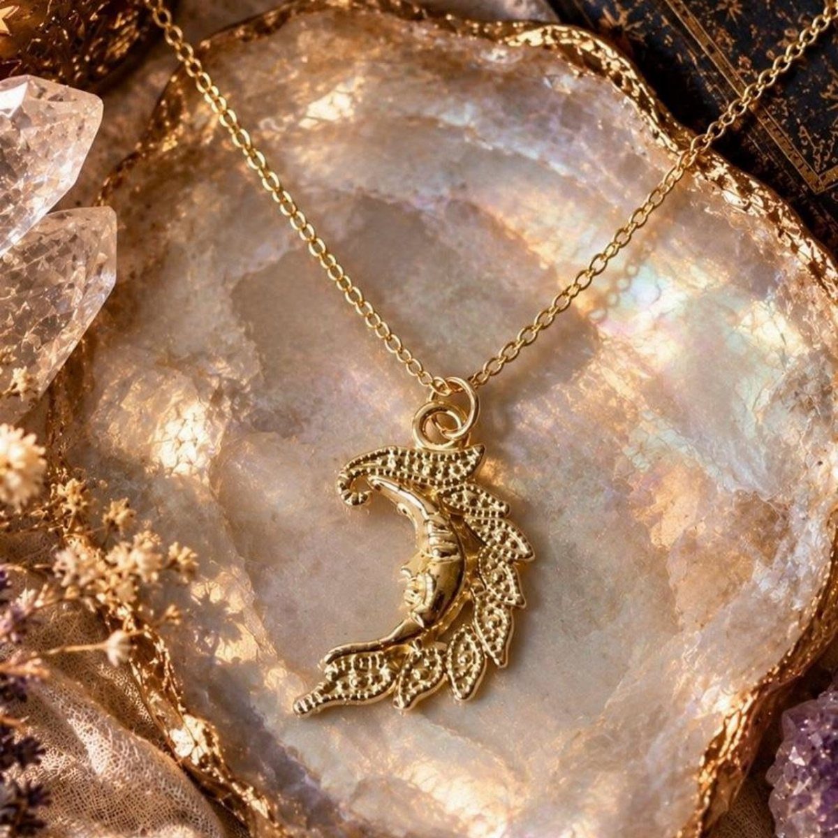 A gold crescent moon pendant necklace resting on a sparkling, iridescent geode surface.