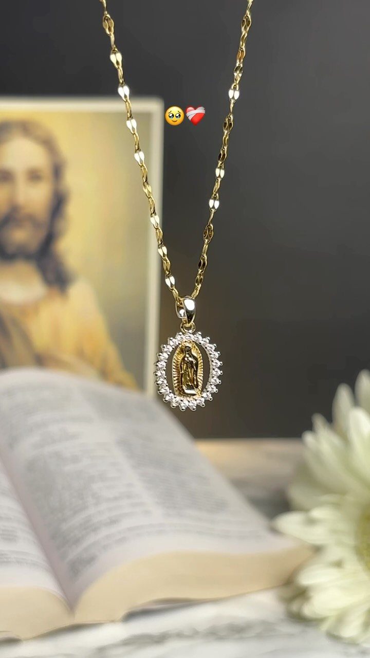 Gold necklace with a Virgin of Guadalupe pendant hanging over an open book.
