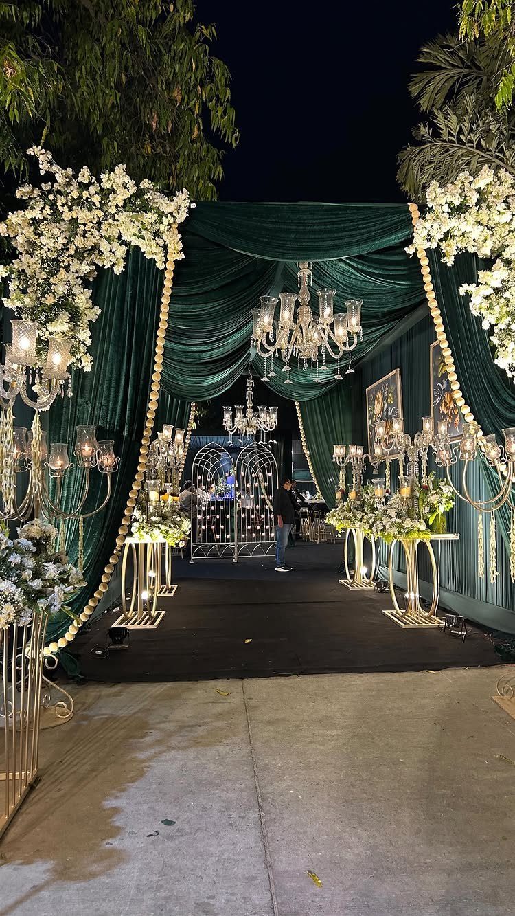 Dark green velvet drapes and white flowers frame a grand wedding entrance with crystal chandeliers.
