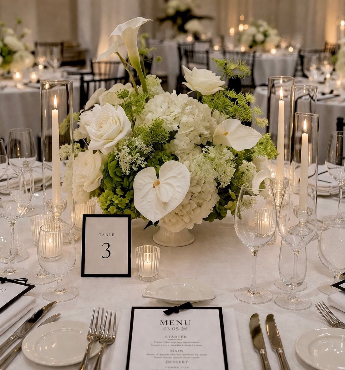 White and green floral centerpiece with roses and hydrangeas on a wedding table setting.