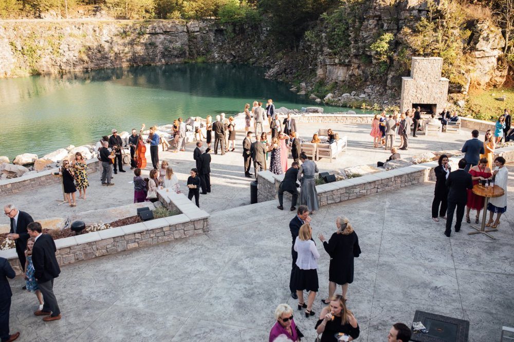 Guests mingling on a stone patio at a wedding venue located inside a rocky quarry.