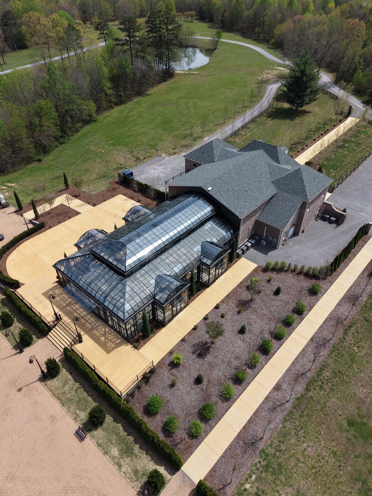 Aerial view of a large estate with a glass conservatory and manicured green grounds.