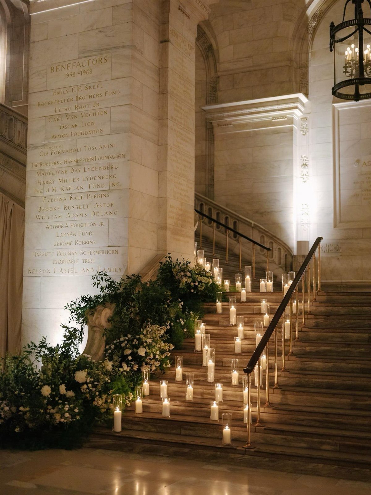 Stone staircase decorated with many glowing candles and lush white floral arrangements.