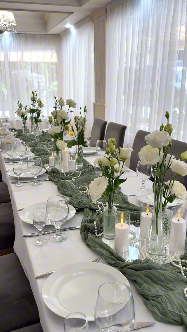 7 Long Table Wedding Reception Ideas for Outdoor Celebrations 7 A long wedding reception table decorated with white roses, candles, and a sage green fabric runner.