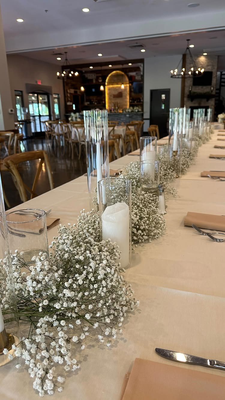 7 Long Table Wedding Reception Ideas for Outdoor Celebrations 6 A long wedding reception table decorated with white baby's breath and tall glass candle cylinders.