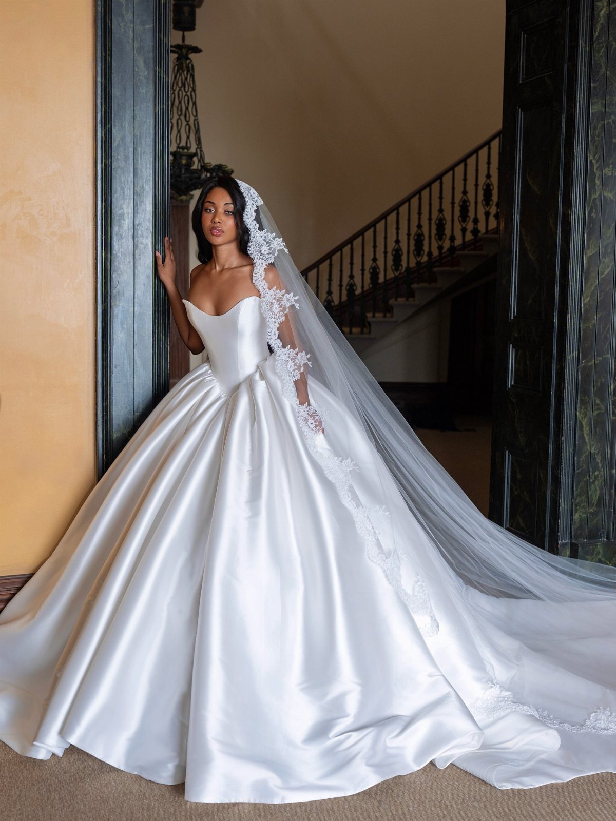 Woman in a white satin ball gown wedding dress with a long lace veil.