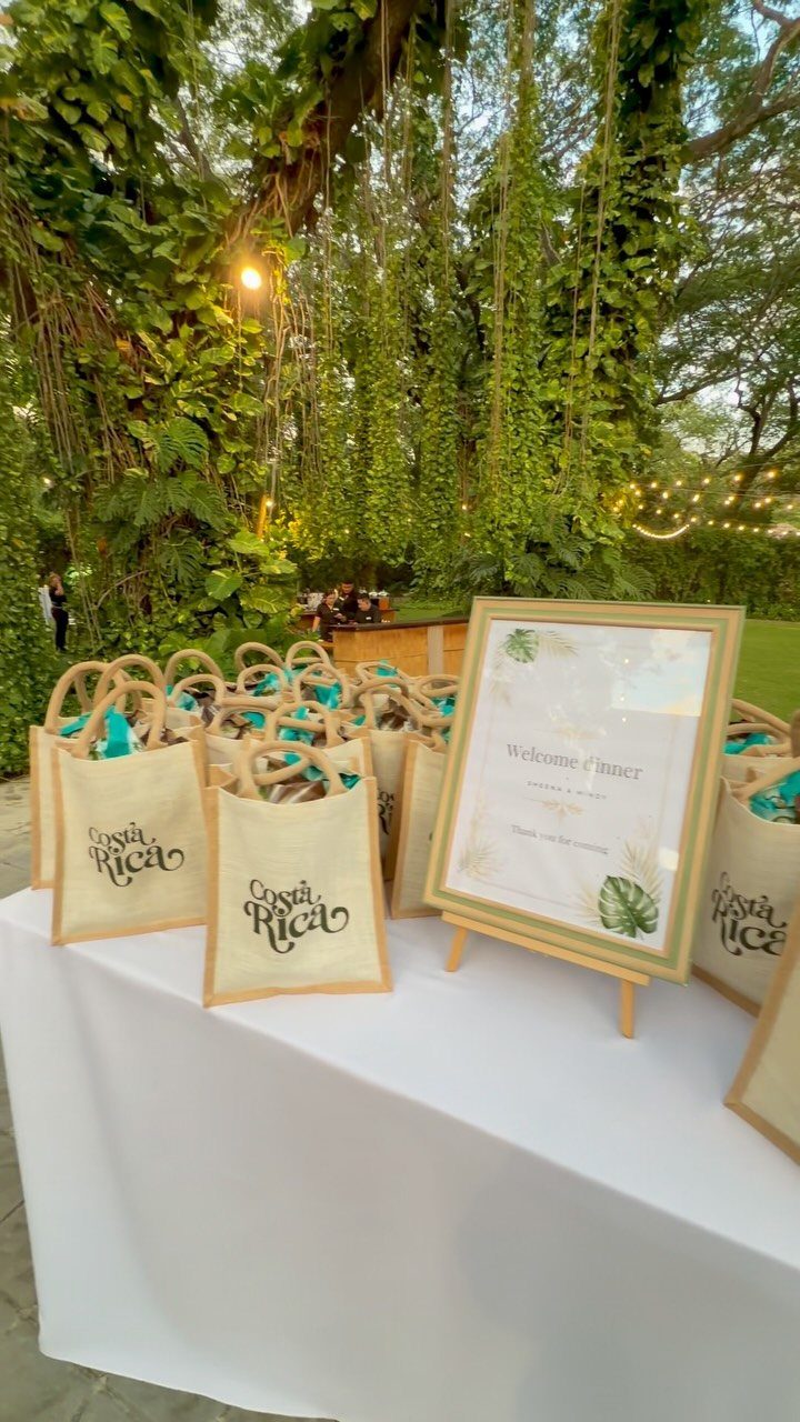 Rehearsal Dinner Gift Ideas: 9 Ways to Thank Your People 9 Small burlap gift bags with teal tissue paper arranged on a white table in a garden.