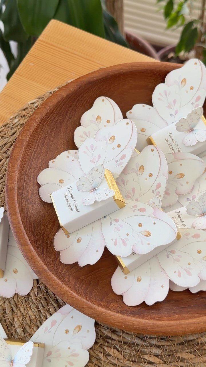 Rehearsal Dinner Gift Ideas: 9 Ways to Thank Your People 7 Butterfly-shaped personalized chocolate favors resting inside a large wooden bowl on a table.