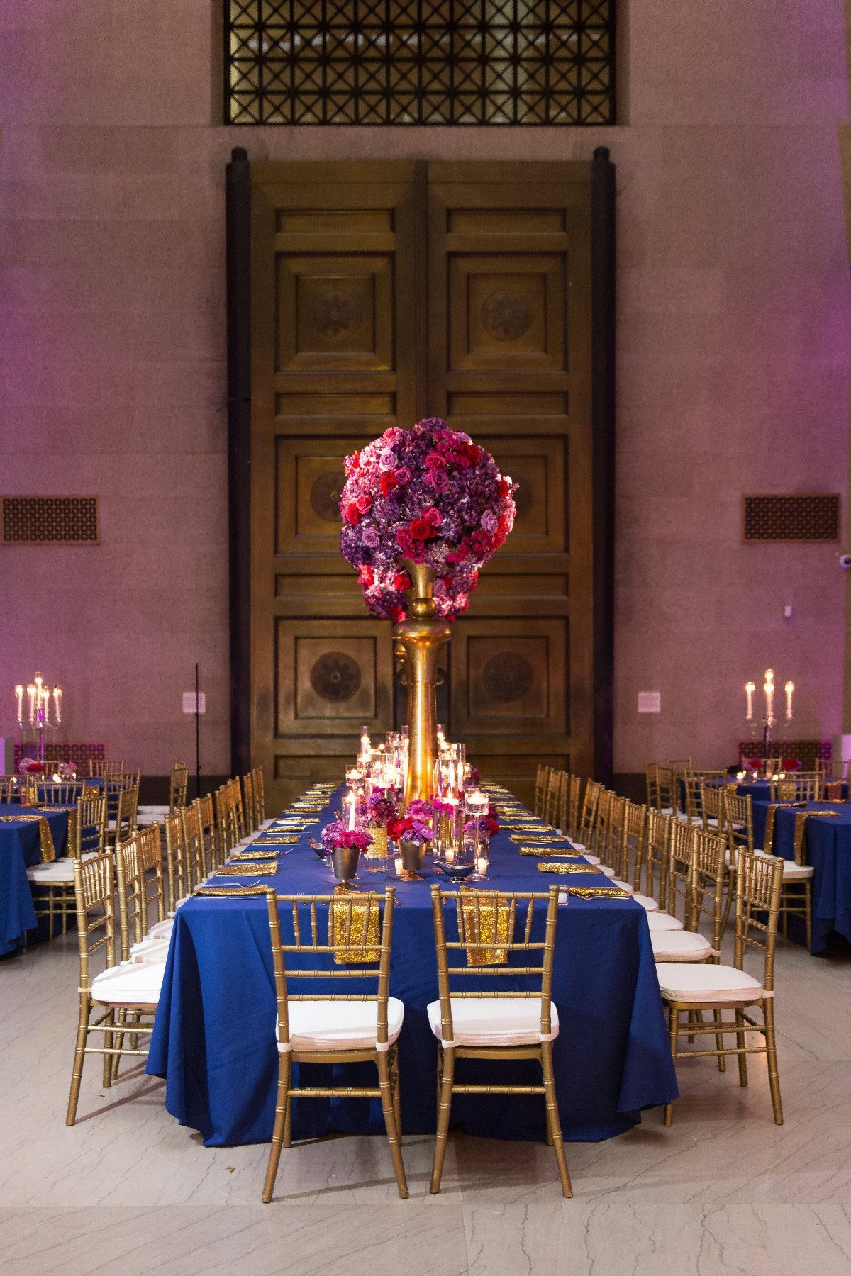 Wedding Colors Royal Blue: 9 Ideas for Your Reception 7 A long wedding banquet table with royal blue linens and large purple floral centerpieces.