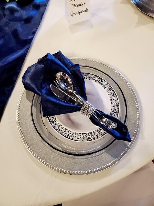 Wedding Colors Royal Blue: 9 Ideas for Your Reception 3 A formal wedding table setting with silver charger, patterned plate, and royal blue satin napkin.