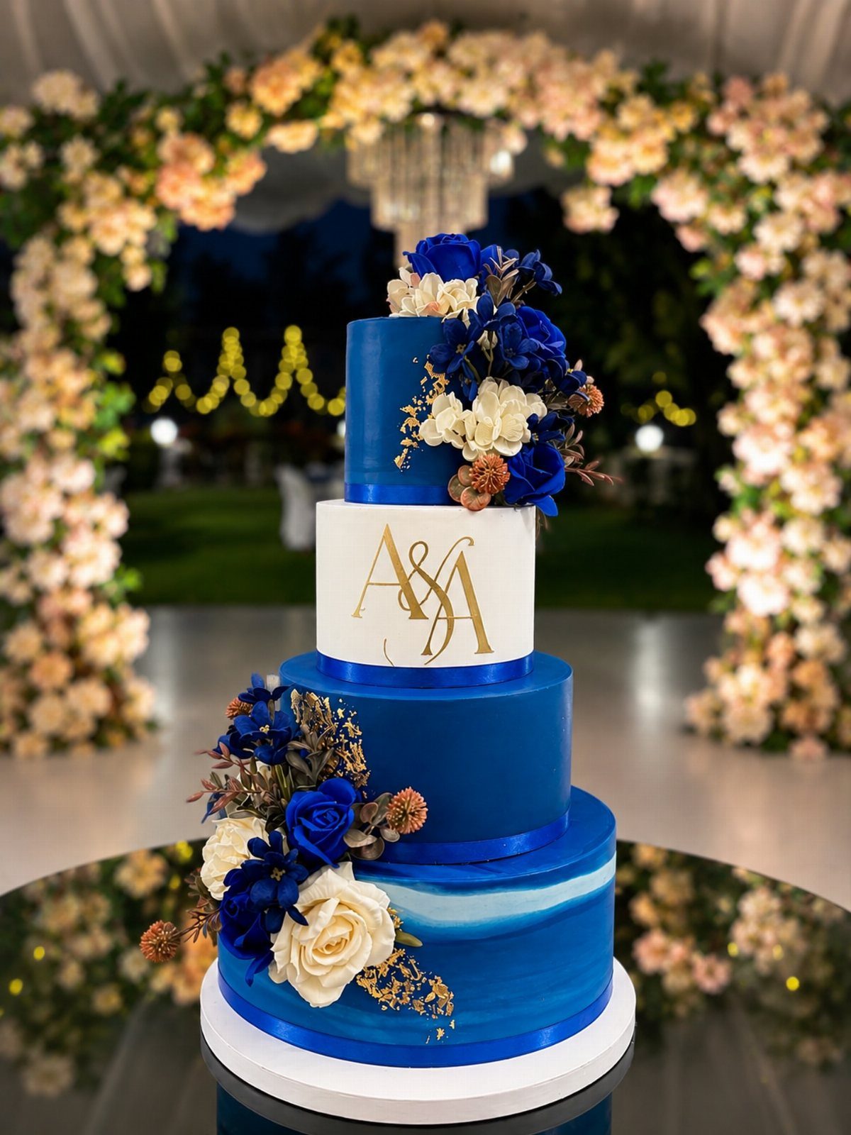 Wedding Colors Royal Blue: 9 Ideas for Your Reception 6 A four-tier royal blue and white wedding cake decorated with flowers and gold monogrammed initials.