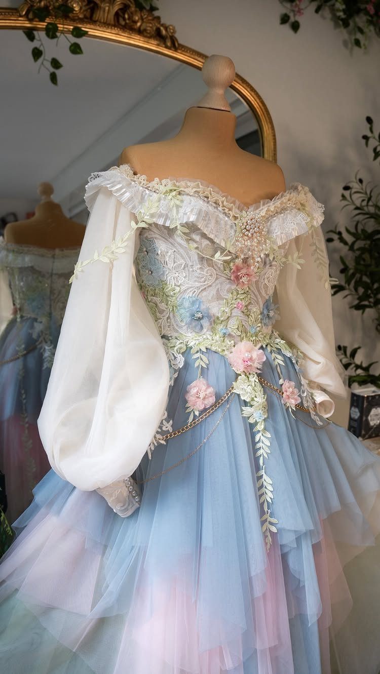 A light blue and pink tulle wedding dress with floral embroidery on a mannequin.