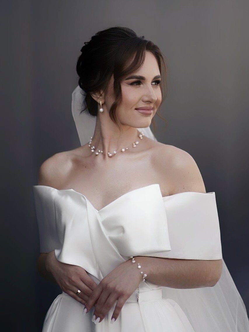 Wedding Dress with Pearl Necklace: 5 Styling Ideas That Work 3 A woman in a white wedding dress wearing a pearl choker necklace and pearl bracelet.