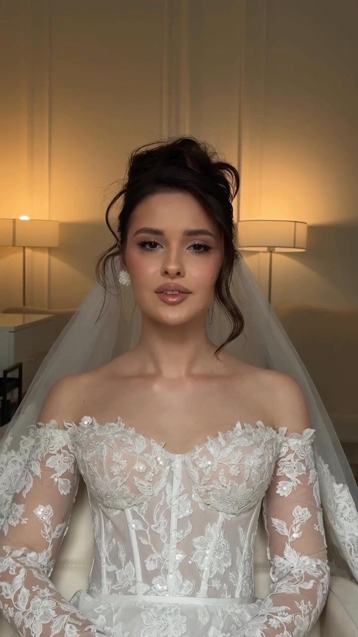 A bride in a lace wedding dress with an elegant updo and sheer veil.