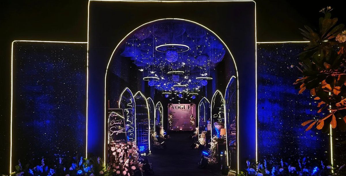 A dark arched entryway glowing with blue lights and sparkling star-like patterns.