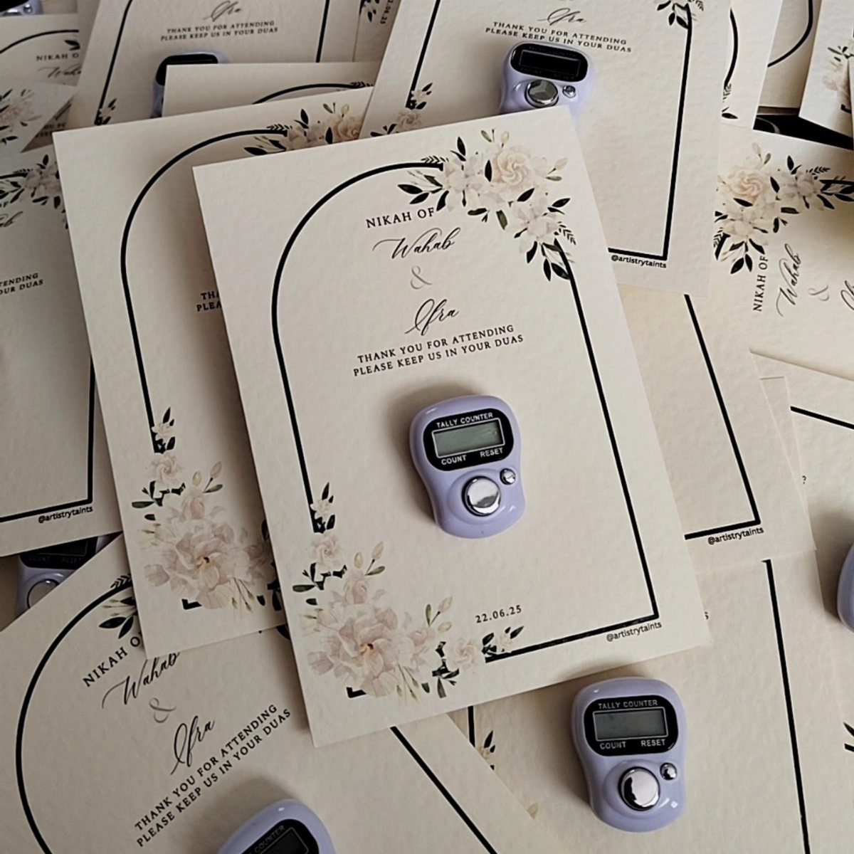 Small purple digital tally counters attached to floral printed wedding thank you cards.