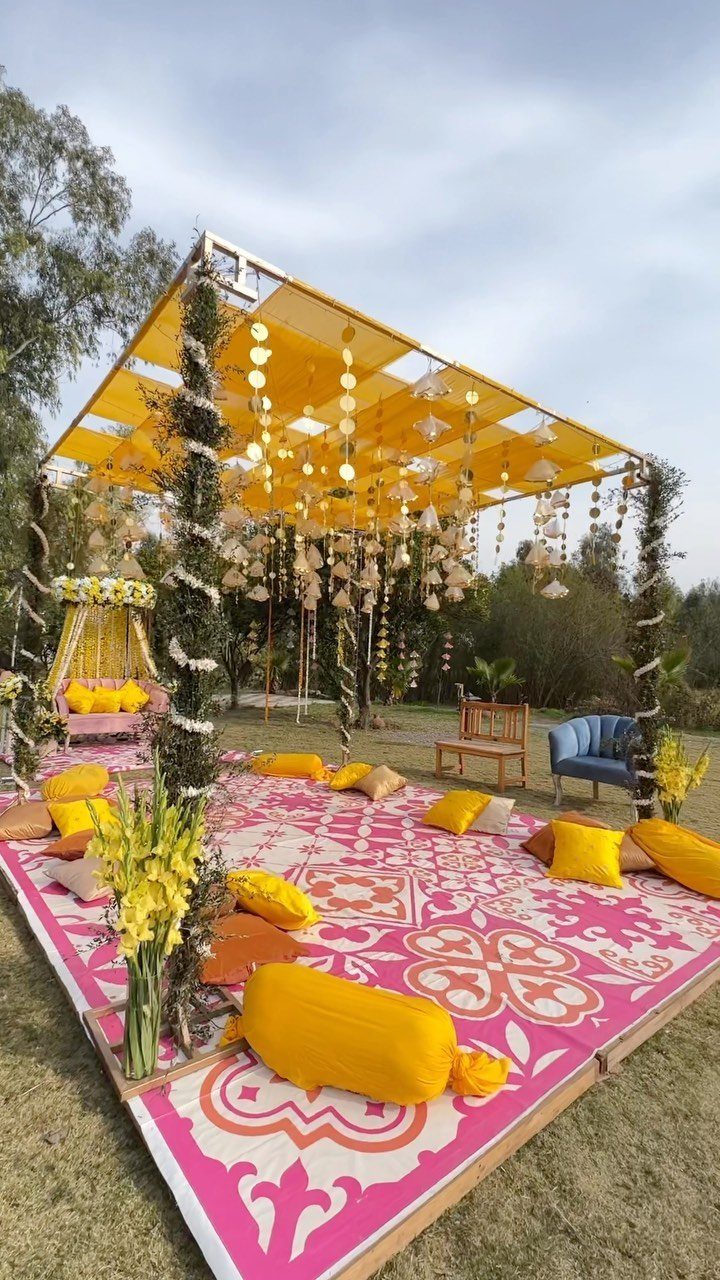 Yellow and Pink Wedding Colors: 6 Ideas for a Sunny Celebration 6 Outdoor event decor with pink patterned flooring, yellow cushions, and a yellow floral canopy under a cloudy sky.