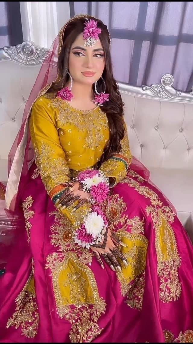 Yellow and Pink Wedding Colors: 6 Ideas for a Sunny Celebration 3 Woman in yellow and pink embroidered traditional clothing wearing pink floral jewelry while sitting on a sofa.